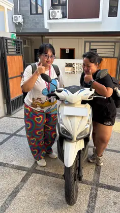 Two customers collecting a white scooter outside their guesthouse